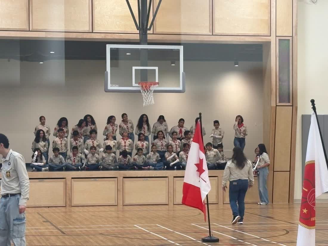 Scouts in uniform on the SMCC gymnasium stage, with the Canadian flag in front